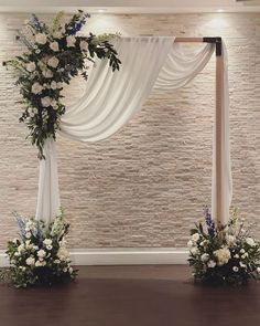 the wedding arch is decorated with white flowers and greenery for an elegant touch to the venue