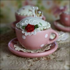 a pink teacup with a red rose in it on a lace doily tablecloth