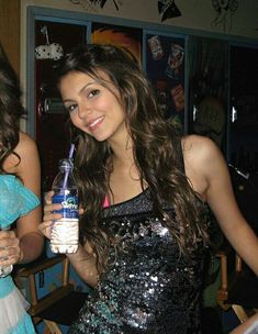 two beautiful young women standing next to each other holding onto drinks in their hands and posing for the camera