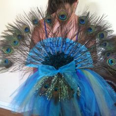 a woman wearing a blue dress with peacock feathers on it