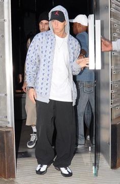 a man in a blue and white hoodie is entering a building with his hand on the door