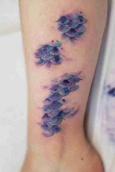 a watercolor tattoo on the leg of a woman with blue fish swimming in it