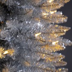 a close up view of a silver and gold christmas tree with lights on it's branches