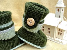 two green knitted boots with a button on the side and a small white house in the background