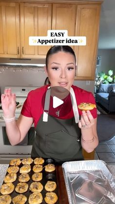 a woman in an apron is holding up her hand and looking at pastries on a baking sheet