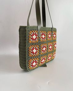 This beautiful handmade knitted bag is an absolute must-have for any fashion-conscious woman!  Its eye-catching floral pattern in red, white, and orange on a green background is sure to turn heads wherever you go.  The bag is lined with high-quality material that ensures all your important items are stored safely and protected.  The interior pockets provide additional storage space for small items such as keys, cell phone, or lipstick.  The faux leather strap provides a comfortable carrying experience and a stylish look.  This bag is the perfect accessory for any occasion! ✪Handmade handle bag made of polyester and mercerised cotton. ✪Size Width: 32 cm Height: 25 cm Depth: 60 cm ✪Material Bag: polyester, mercerised cotton Interior: With lining and felt