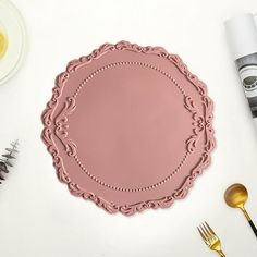 a pink plate sitting on top of a table next to silverware and utensils