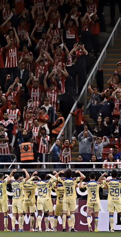 a group of men standing on top of a soccer field holding hands up in the air