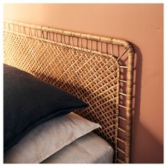 a wicker headboard with two pillows on it and a pink wall in the background