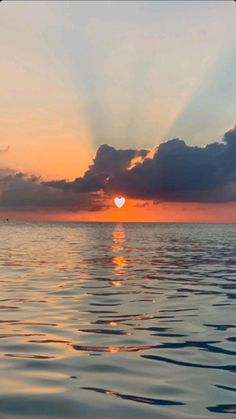 the sun is setting over the ocean with clouds in the sky and water below it