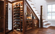 a wine cellar in the corner of a room with stairs leading up to an open door