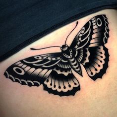 a black and white butterfly tattoo on the side of a woman's stomach,