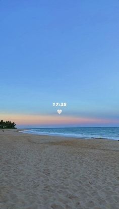 two people are walking on the beach at sunset