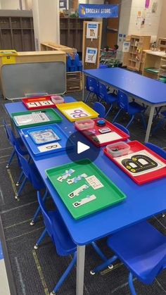 tables and chairs are lined up in a classroom with blue desks, green table tops, and colorful folders on them