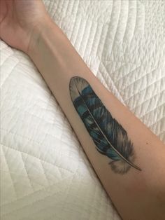 a person's arm with a tattoo that has a blue and white feather on it