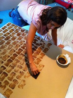 a woman is painting on the floor with brown paint