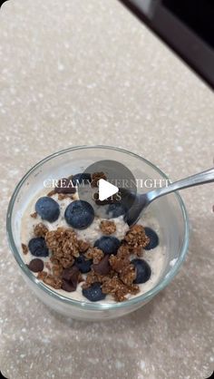 a glass bowl filled with cereal and blueberries on top of a white countertop