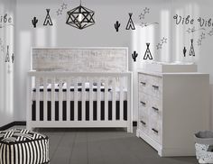 a baby's room with black and white wall decals on the walls, including a crib