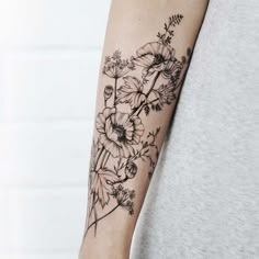 a woman's arm with flowers and leaves tattooed on the left side of her arm