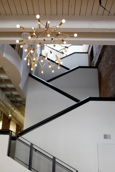 a large chandelier hanging from the ceiling in a room with white walls and black railings