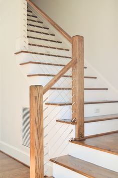 a wooden stair case next to a white wall