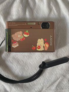 a camera with some stickers on it sitting on a bed next to a cord