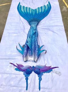 two blue and purple glass sculptures sitting on top of a white cloth covered tablecloth