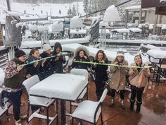 a group of people standing around a table covered in snow