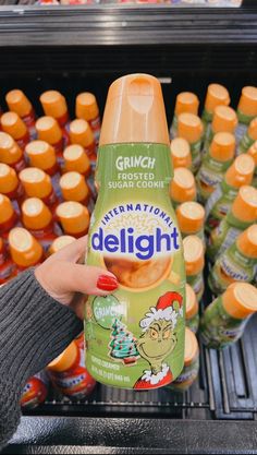 a person holding up a bottle of delignt in front of some orange juice