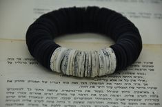 a black and white bracelet sitting on top of an open book with writing in it