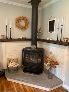 a wood burning stove sitting on top of a wooden floor next to a wall filled with candles