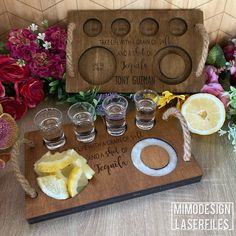 a wooden cutting board topped with glasses and lemon slices