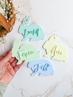 someone holding up some bunny shaped magnets with the word easter written on them in different colors