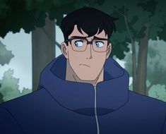 a man wearing glasses and a hoodie in front of trees with blue eyes looking at the camera