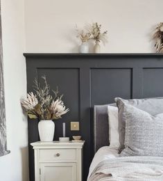 a bed with two vases on top of it next to a night stand and nightstand