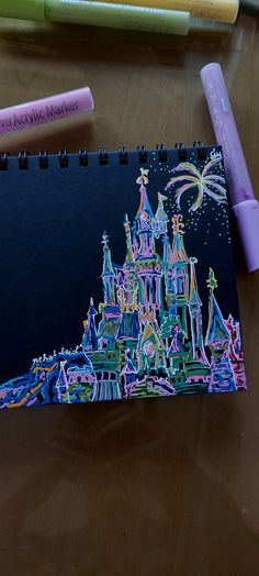 a drawing of a castle is shown on a desk with markers and crayons