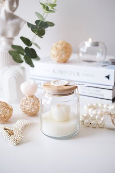 a jar filled with white candles sitting on top of a table next to other items