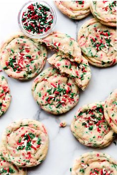 cookies with sprinkles and red, white and green sugar are on a marble surface