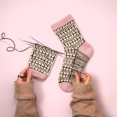 two hands are holding up socks with knitting needles