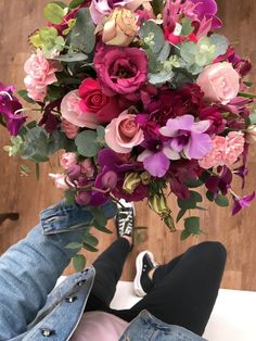 a person holding a bouquet of flowers in their lap, with one foot on the ground