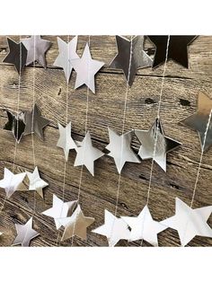 some metal stars hanging from strings on a wooden wall