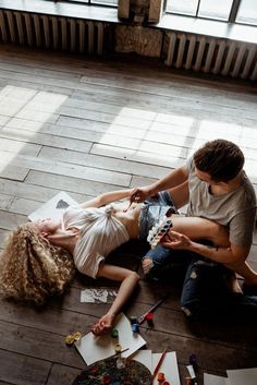 two people sitting on the floor with art supplies