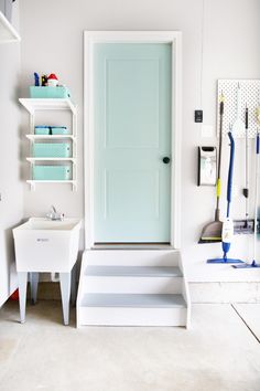 a white room with a blue door and some shelves on the wall next to it