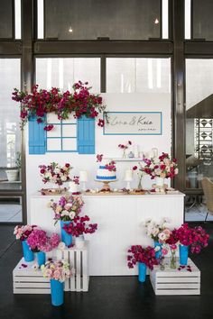 a table topped with lots of flowers next to blue vases filled with red and white flowers