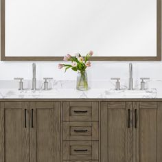 a bathroom vanity with two sinks and a large mirror above it that has flowers in a vase on top