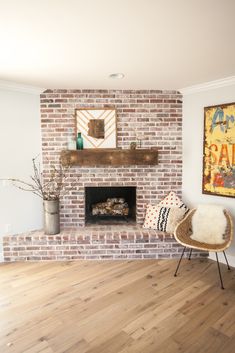 a living room with a brick fireplace and wooden floors in front of a painting on the wall