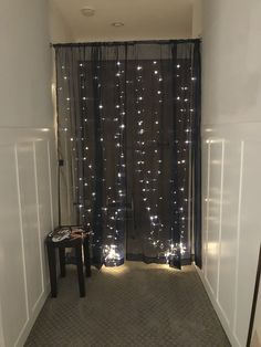 a hallway with lights on the curtains and a small table in front of the door