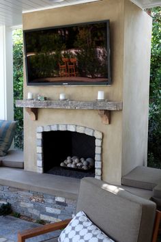 an outdoor fireplace with a television mounted above it