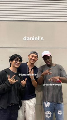 three young men standing next to each other in front of a wall with the name danielle's on it