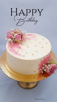 a birthday cake decorated with pink flowers and pearls on a gold platter that says happy birthday